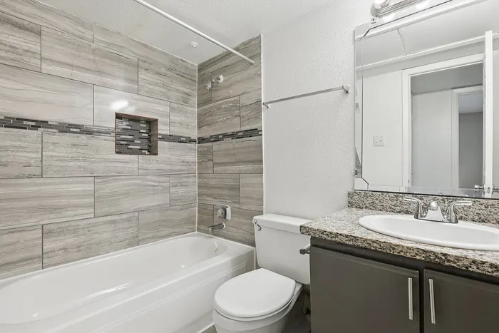 Elegant bathroom with modern granite countertop, sleek vanity, and stylish tiled bathtub showcasing contemporary design.