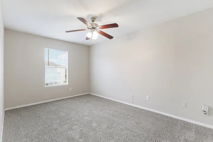 Bright, spacious room featuring plush carpet and a sleek ceiling fan, perfect for a cozy bedroom or home office.