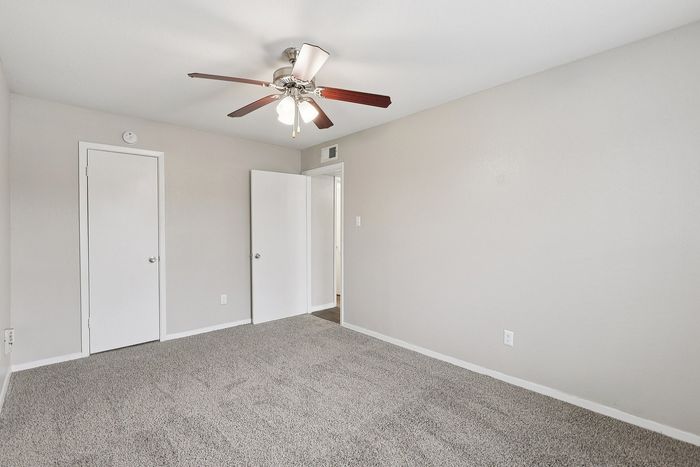 Bright and airy bedroom featuring soft carpet flooring, fresh neutral walls, and a stylish ceiling fan.