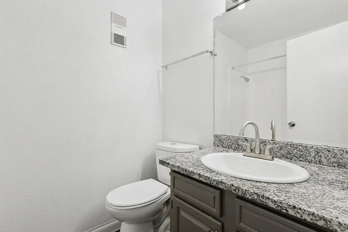 Elegant bathroom featuring a sleek granite countertop, modern sink, and spacious mirror for a contemporary feel.