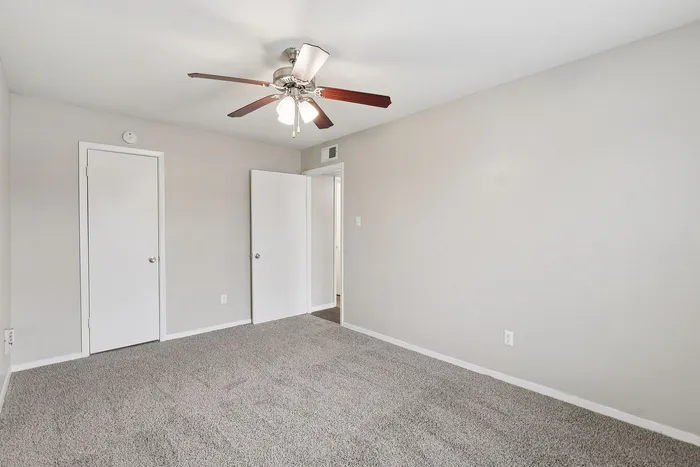 Bright and spacious bedroom featuring plush carpet and modern ceiling fan for comfort and style.