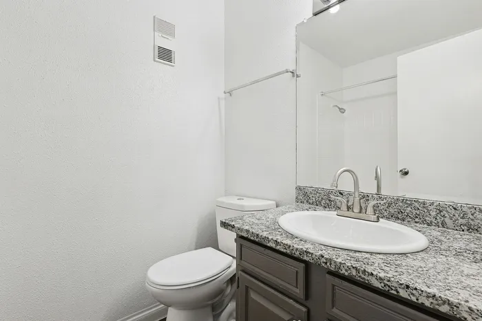 Sleek bathroom with modern white fixtures and elegant granite countertop.
