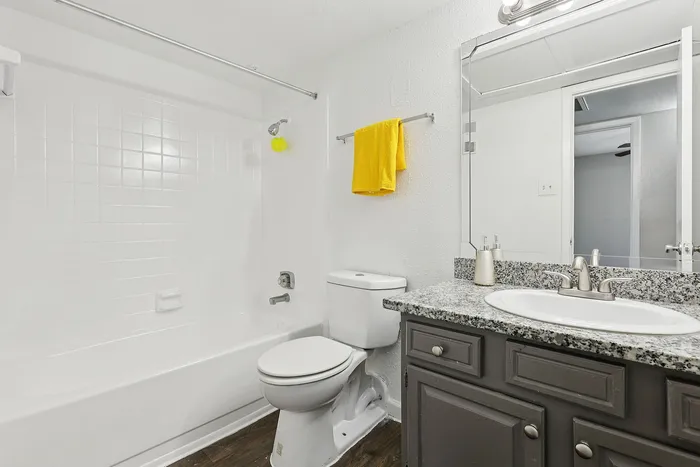 Modern bathroom featuring a sleek marble countertop, elegant fixtures, and a refreshing combination of white tiles and yellow accents.