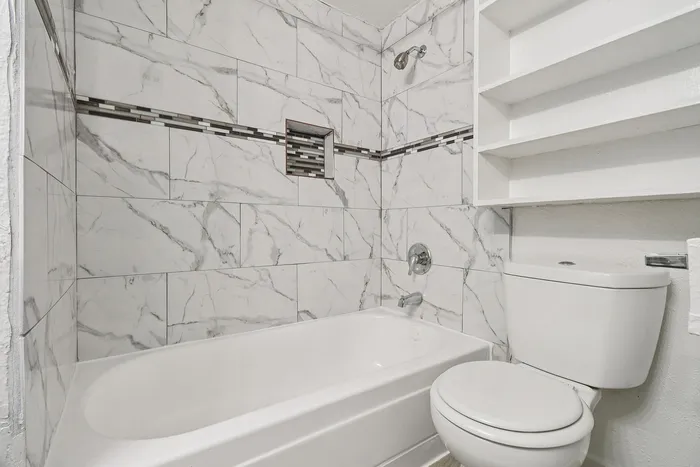 Elegant bathroom featuring modern marble tile design with built-in shelving, perfect for a luxurious living experience.