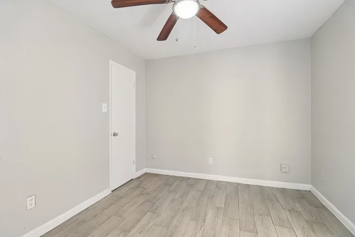 Bright and airy room with modern wood flooring and a sleek ceiling fan, perfect for a cozy bedroom setup.