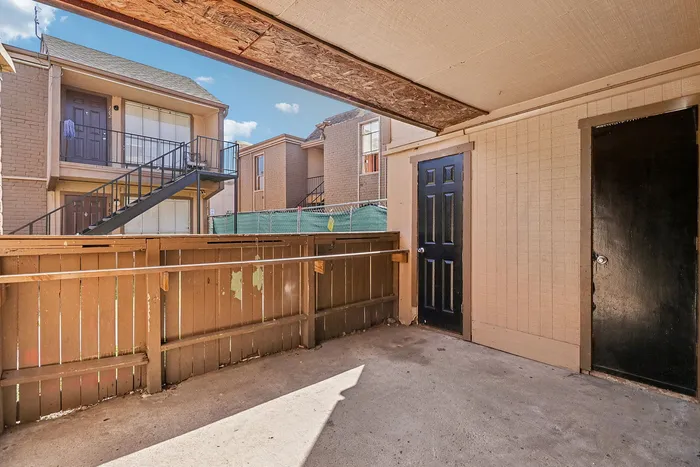 Inviting apartment balcony with a view of neighboring buildings and clear blue skies, offering privacy and outdoor relaxation space.