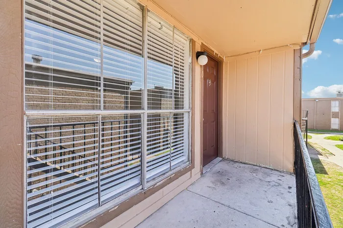 Inviting apartment entrance with large window and charming balcony, perfect for relaxation.