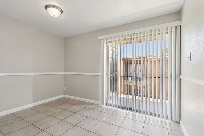 Bright dining area with elegant tile flooring, modern ceiling light, and sliding glass doors leading to a balcony with a view.