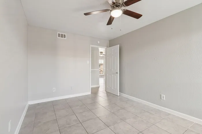 Bright and airy room with modern ceiling fan and elegant tile flooring, ready to be personalized.