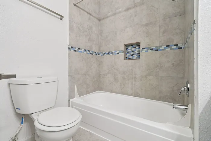 Elegant bathroom featuring modern tilework with blue accents, spacious bathtub, and sleek fixtures.