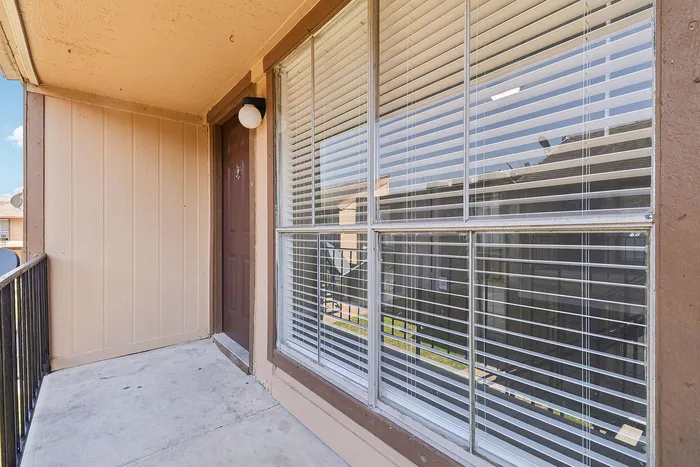 Inviting balcony with stylish wooden paneling and large windows offering a view of the vibrant surroundings.