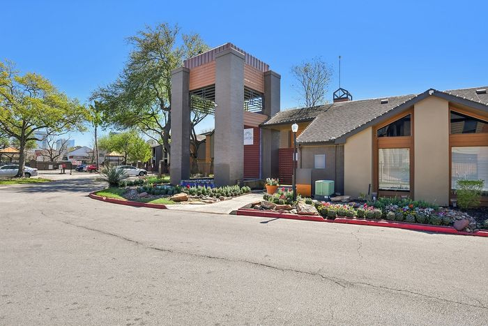 Charming residential entrance with lush landscaping and modern architectural features, offering a welcoming community vibe.
