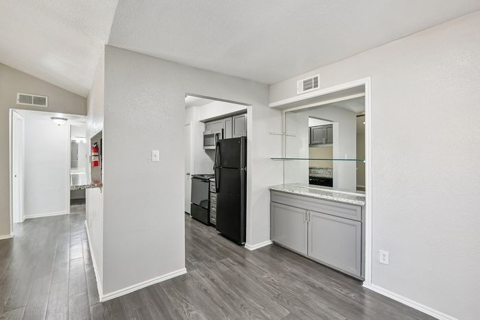 Modern apartment kitchen with sleek black appliances, elegant granite countertops, and contemporary gray cabinetry, offering a stylish and functional space.