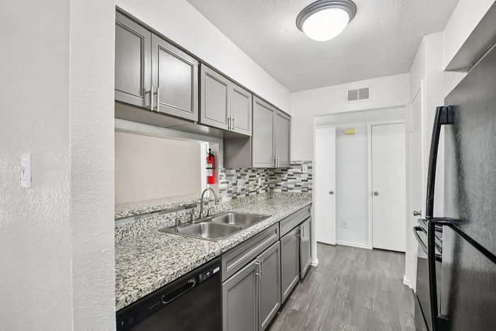 Sleek modern kitchen with granite countertops, elegant cabinetry, and stylish backsplash creating a sophisticated cooking space.