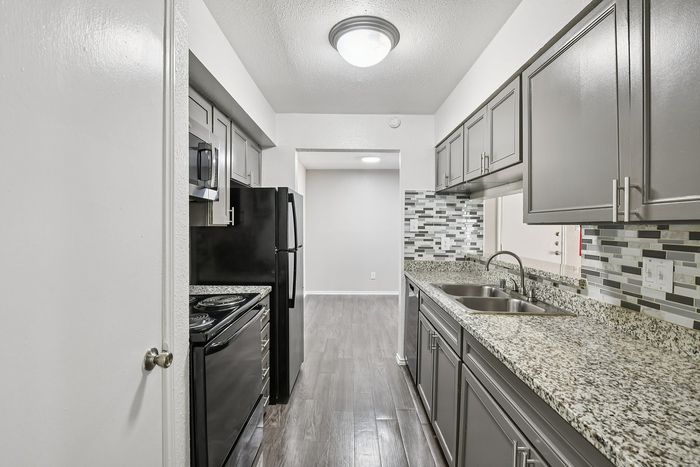 Modern kitchen with sleek gray cabinetry, granite countertops, and stainless steel appliances complemented by elegant tile backsplash.