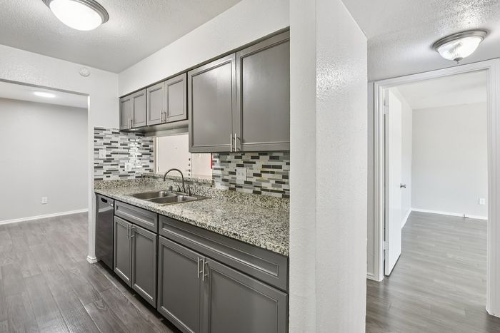Chic kitchen with modern gray cabinetry, elegant granite countertops, and a stylish mosaic tile backsplash.