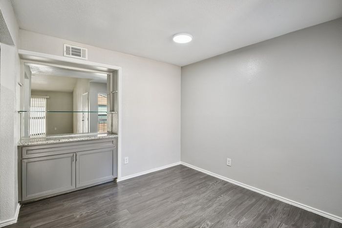 Elegant apartment space showcasing modern grey cabinetry, sleek glass shelving, and sophisticated wood flooring.