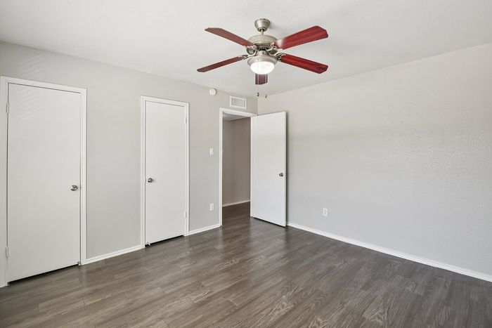 Bright and airy bedroom with elegant wooden flooring, a stylish ceiling fan, and smooth white doors, perfect for modern living.