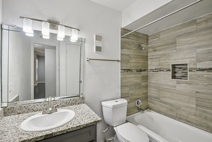 Modern bathroom showcasing elegant stone-tiled walls, a sleek granite countertop, and contemporary lighting fixtures.