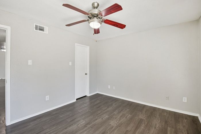 Charming room with elegant wood flooring and a modern ceiling fan, offering a bright and inviting space.