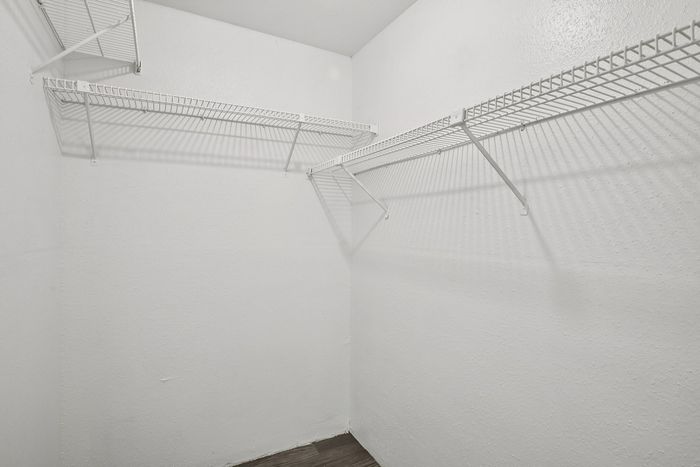Spacious walk-in closet with white wire shelving, perfect for organized storage solutions.