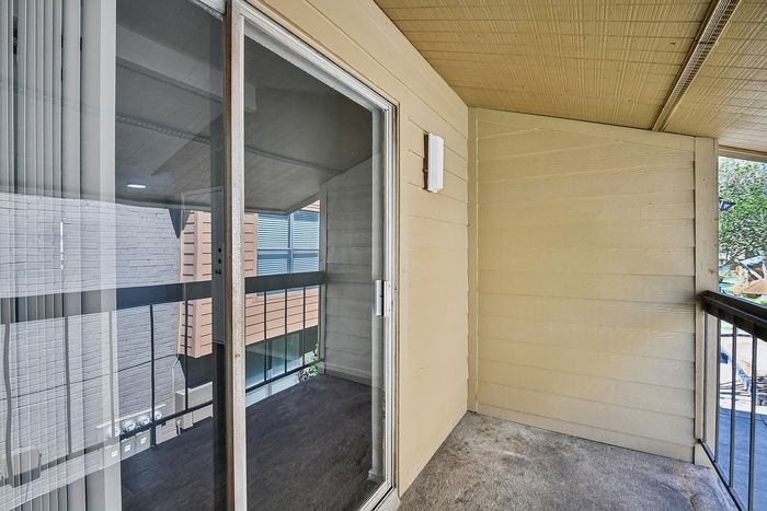 Cozy balcony space featuring a large sliding glass door with scenic neighborhood views.
