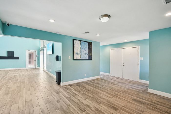 Bright, modern entryway with elegant wood flooring, vibrant teal walls, and contemporary artwork, perfect for a welcoming home environment.