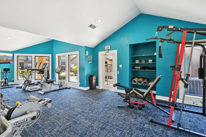 Inviting fitness center with vibrant blue walls, state-of-the-art exercise equipment, and large windows for ample natural light.