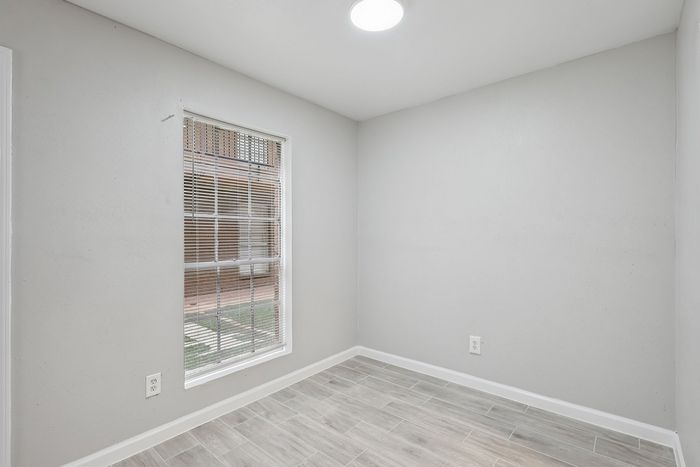 Bright and inviting room with elegant tile flooring and ample natural light from a large window with blinds.