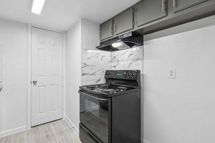 Modern kitchen with sleek black appliances, stylish marble tile backsplash, and ample cabinet space.