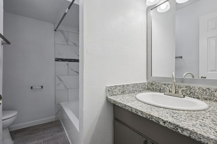 Modern bathroom with elegant granite countertop, sleek faucet, and contemporary tiled shower.