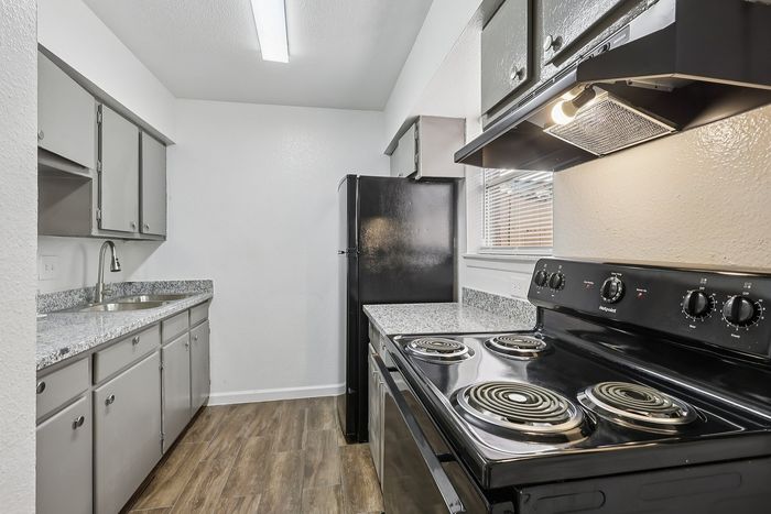 Modern kitchen with sleek black appliances, granite countertops, and ample cabinetry, offering a bright and functional cooking space.