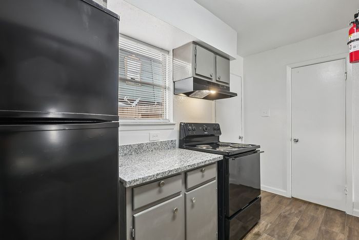 Modern kitchen with sleek black appliances, granite countertop, and elegant cabinetry, offering a stylish cooking space.