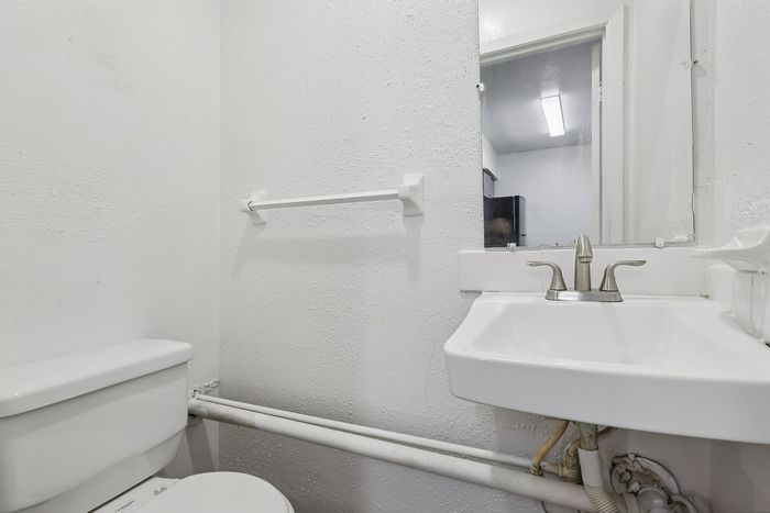 Bright, minimalist bathroom featuring a sleek white sink and modern fixtures, offering a clean and refreshing atmosphere.