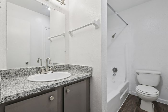 Modern bathroom with sleek granite countertop, elegant fixtures, and a pristine bathtub offering a fresh and inviting ambiance.