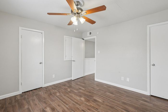 Bright and airy room with elegant wood-style flooring, a modern ceiling fan, and neutral walls offering versatile decor possibilities.