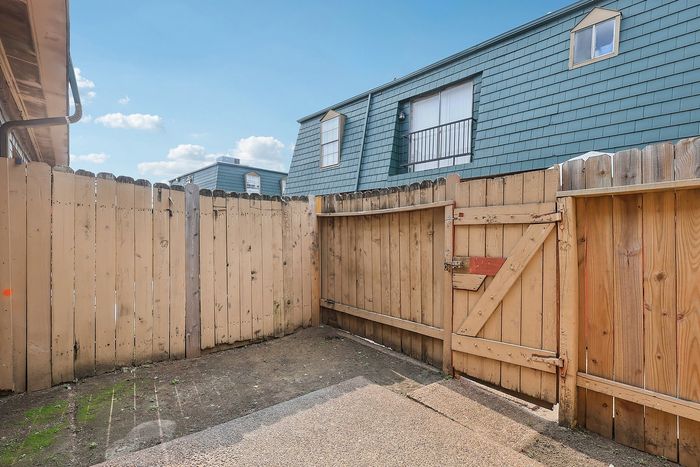 Charming private fenced patio with rustic gate, offering a cozy outdoor space perfect for relaxation and enjoyment.