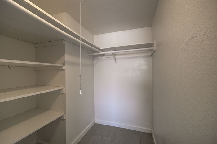 Spacious walk-in closet with built-in shelves and ample hanging space.