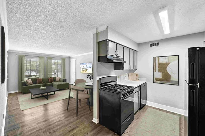Modern apartment interior showcasing an open-plan kitchen and cozy living area with a sleek black stove, stylish furniture, and large windows inviting natural light.