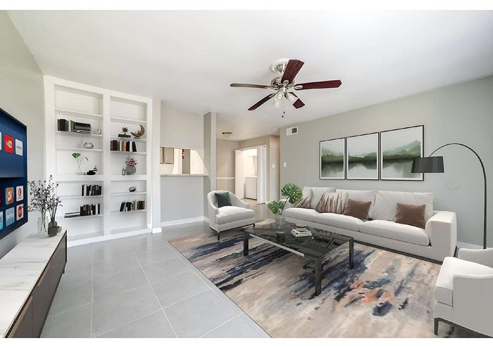 Bright and modern living room with elegant shelving, cozy seating area, stylish decor, and a sleek ceiling fan.