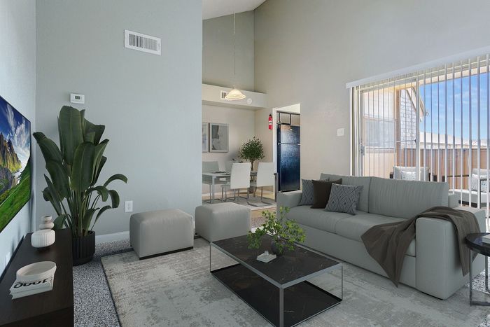 Modern living room with sleek gray decor, spacious seating area, and abundant natural light through large glass doors leading to a balcony.