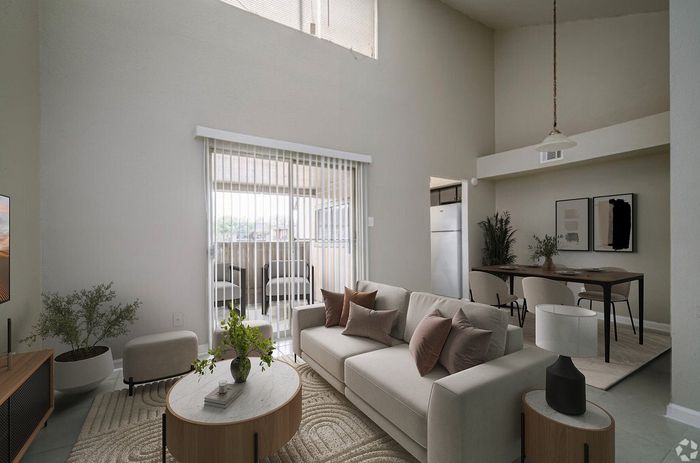 Modern living room with high ceilings, cozy seating, and an adjacent dining area, featuring stylish decor and abundant natural light.