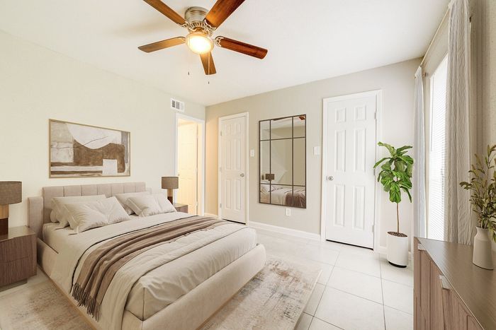 Elegant bedroom with a cozy bed, modern decor, and natural light streaming through large windows.