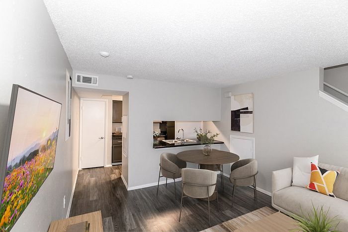 Modern living room with stylish dining area and sleek open kitchen, showcasing elegant decor and comfortable seating.