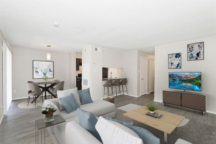 Contemporary open-plan living room with elegant dining area, cozy gray seating, and modern kitchen bar stools for a welcoming home ambiance.