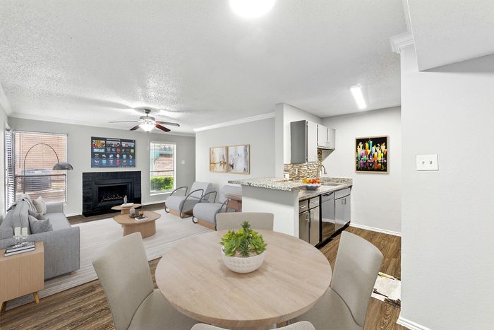 Bright and modern open-concept living and kitchen area with elegant furnishings, stylish decor, and a cozy fireplace&mdash;ideal for relaxation and entertaining.