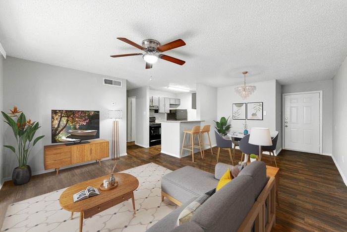 Modern open-concept living room with elegant wooden flooring, stylish furnishings, and a chic dining area adjacent to a sleek, well-equipped kitchen.