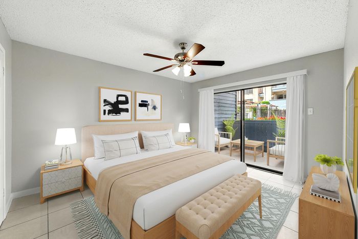 Inviting bedroom with modern decor, featuring a cozy bed, stylish art, and a private patio view through sliding glass doors.