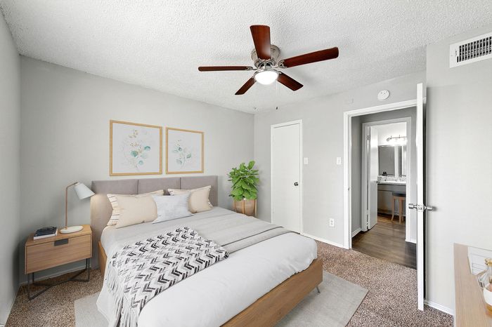Chic bedroom with plush bed, modern decor, and a cozy ambiance enhanced by warm lighting and a ceiling fan.