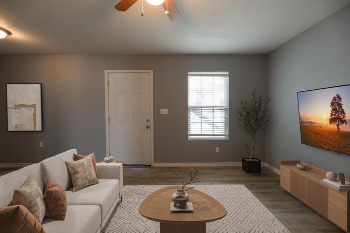 Inviting living room with modern decor featuring a cozy sofa, stylish coffee table, and a wall-mounted TV showcasing a serene landscape.